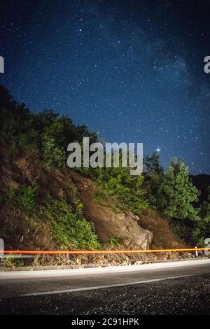 Long exposure fast moving light trails on highway,with milky way and stars Stock Photo