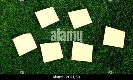 group of yellow paper rectangular stickers on green grass top view. copy space. Stock Photo