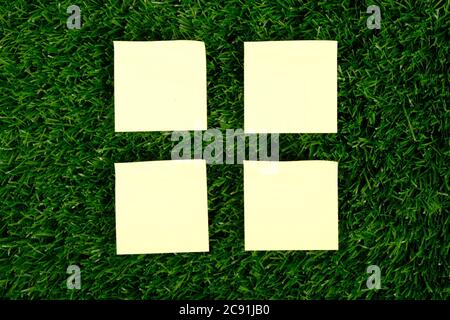 yellow paper rectangular stickers on green grass top view. copy space. Stock Photo