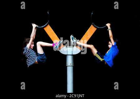 Two boys hanging onto a piece of playground furniture. Stock Photo