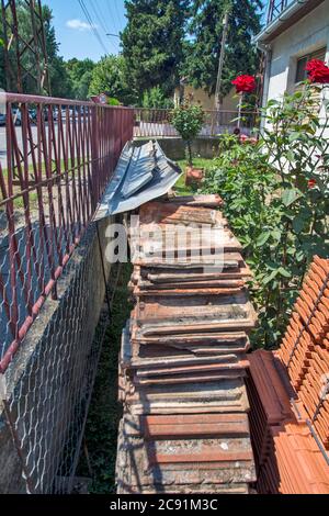 Home yard and stored old and new tiles. The new tile is waiting for the preparation of the supporting wooden construction, which is in progress. Stock Photo