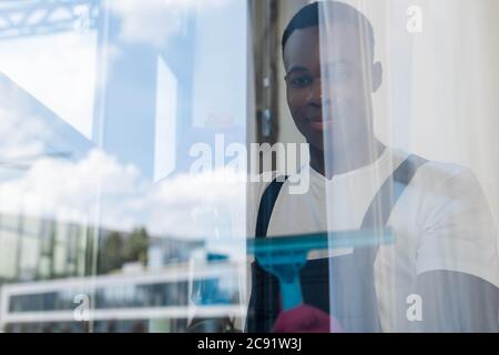 Selective focus of african american cleaner holding squeegee handle while cleaning window in office Stock Photo