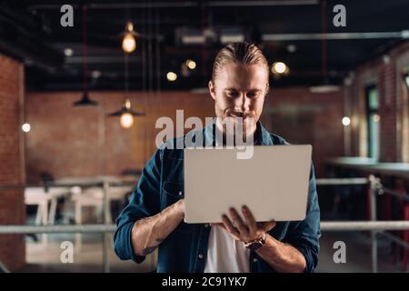 bearded businessman holding and using laptop in modern office Stock Photo