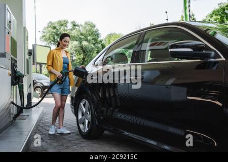Beautiful smiling woman refueling car on gas station Stock Photo