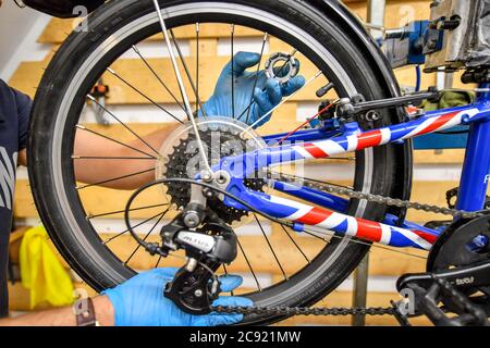 A rear wheel spoke is adjusted inside Briscycle workshop an