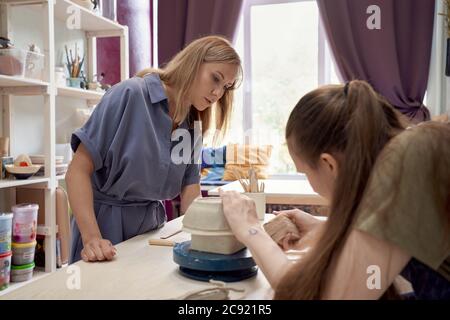 Master-class on making of utensils of clay, one female teaches another on workshop Stock Photo