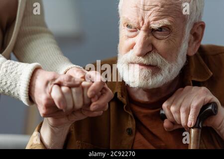 partial view of woman holding hand of senior husband, sick on dementia Stock Photo