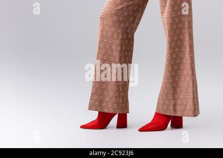 partial view of stylish woman in beige trousers and red boots on grey Stock Photo