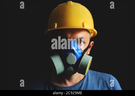Miner in yellow helmet and respirator on black background.Coal industry, safety and protection Stock Photo