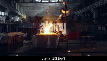 Smelting orange metal in a metallurgical plant. Liquid iron from the ladle Stock Photo