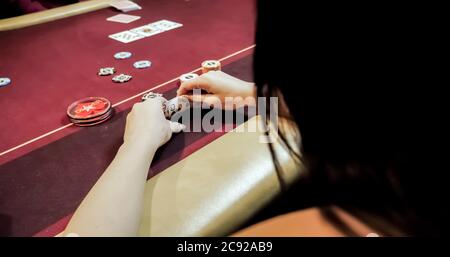 Dealer sitting in a casino at table while holding and distributing cards Stock Photo