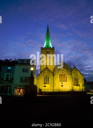 St Mary's church, High Street, Tenby, Pembrokeshire, Wales. East end, tower, and shops floodlit in late evening Stock Photo