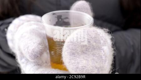 Hot drink in plastic cup in hands on bright background Stock Photo