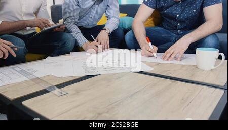 business, people, architecture and team work concept - close up of architects team hands pointing finger to blueprint at office Stock Photo