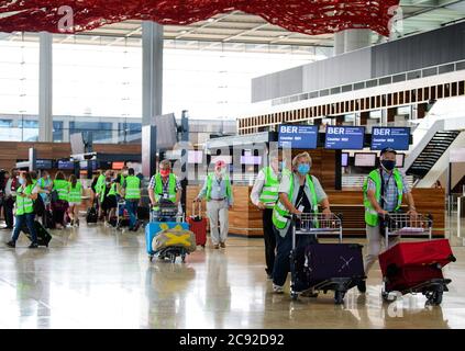 28 July 2020, Brandenburg, Schönefeld: Extras in green high-visibility vests go in for a test run at Terminal 1 of Berlin-Brandenburg Airport (BER). In the second phase of the Operational Readyness and Airport Transfer (ORAT), some 500 to 600 airport employees and 400 volunteers rehearsed standard processes for passengers from check-in to security control to boarding and deboarding (arrival). Photo: Soeren Stache/dpa-Zentralbild/dpa Stock Photo