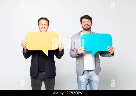 Portrait of a two satisfied business men holding empty speech bubbles over white background Stock Photo
