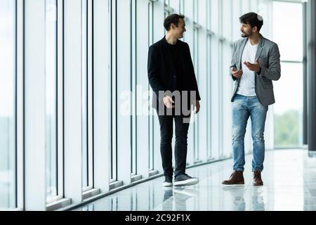Portrait of two concentrated businessmen partners dressed in formal suit walking and having conversation Stock Photo