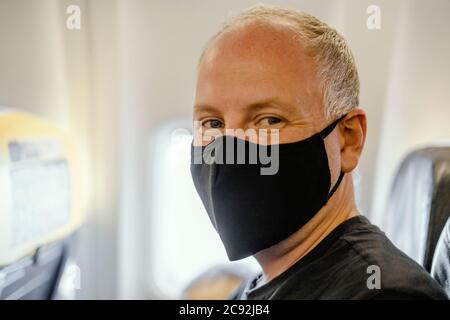Man sitting in the airplane wearing protective face mask Stock Photo