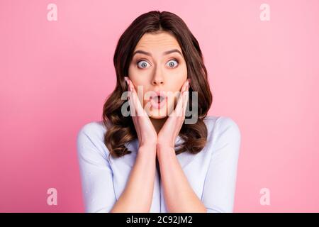 Closeup photo of shocked attractive lady wavy hairdo listen bad news open mouth terrified eyes arms on cheeks wear casual white pullover isolated pink Stock Photo