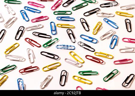 A lot of multi-colored colored paper clips on a white background. Background idea for business. Stock Photo