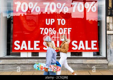 Edinburgh, Scotland, UK. 28 July, 2020. Business and tourism slowly returning to the shops and streets of Edinburgh city centre. Women walk past shop window of Topshop on Princes Street with large sale poster on display. Iain Masterton/Alamy Live News Stock Photo
