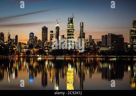 The reflections of the melbourne city skyline at dusk in the still water of albert park lake Stock Photo