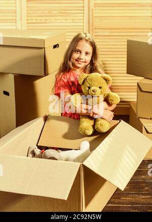 Moving routine. Only true friend. Girl child play with toy near boxes. Packaging things. Move out concept. Stressful situation. Divorce and separation. Family problem. Prepare for moving. Moving out. Stock Photo