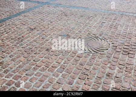 road from a stone blocks, old background texture, iron manhole. Stock Photo