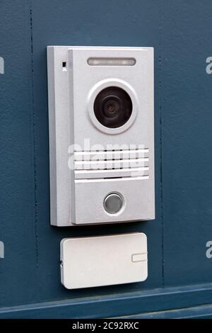 The Intercom with a call button and a light color camera is installed on the iron dark gate with the access card receiver, the side view on the left i Stock Photo