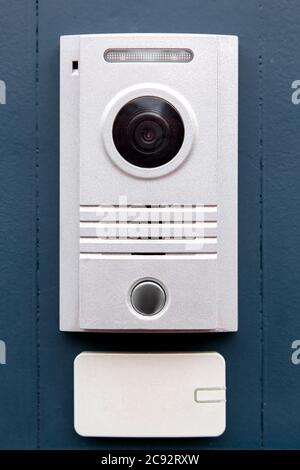 An intercom with a call button and a light colored camera is installed on the iron dark gate with an access card receiver, the front view is close-up. Stock Photo