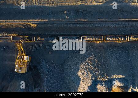 Excavator loads ore into freight cars aerial top view. Stock Photo