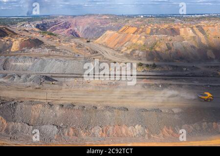 Heavy dump truck carrying the iron ore on the opencast mining aerial view. Stock Photo