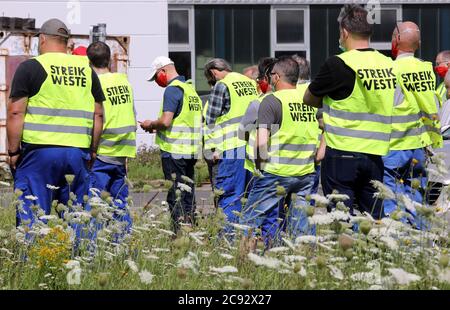 28 July 2020, Mecklenburg-Western Pomerania, Laage: The employees have gathered in front of the plant of the automotive supplier Flamm Aerotec for a warning strike. IG Metall has called for the action in order to achieve better conditions for the 110 employees to leave the plant after the announced closure of the plant at the end of 2020. Photo: Bernd Wüstneck/dpa-Zentralbild/ZB Stock Photo