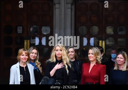 Actress Amber Heard, alongside her sister Whitney Henriquez (fourth right), lawyer Jen Robinson (third right) and girlfriend Bianca Butti (hidden second right), as she gives a statement outside the High Court in London on the final day of hearings in Johnny Depp's libel case against the publishers of The Sun and its executive editor, Dan Wootton. After almost three weeks, the biggest English libel trial of the 21st century is drawing to a close, as Mr Depp's lawyers are making closing submissions to Mr Justice Nicol. . Stock Photo