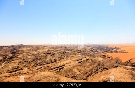 Typical bleak, arid mountainous terrain of the Namib Desert with ochre sand on stratified rock on the Skeleton Coast, Namibia, south-west Africa Stock Photo