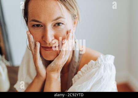 Close up of woman with flour on hands in kitchen, looking at camera Stock Photo