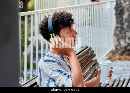 Portrait of a young man with afro hair is listening to music in a park Stock Photo