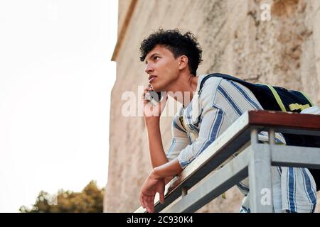 Young man with afro hair is using his smartphone outdoors Stock Photo