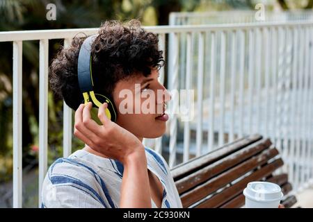 Portrait of a young man with afro hair is listening to music in Stock Photo