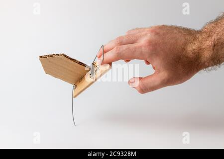 Bank investments and risks. A man's hand caught in a mousetrap with a schematic cardboard house. Copy space. Stock Photo