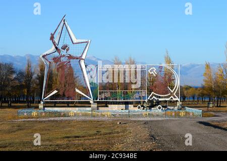 Soviet time monument with the worker and kolkhoz woman in Ottuk, Issyk-Kul Region, Kyrgyzstan. Memorial to the Second World War. Text in Cyrillic. Stock Photo
