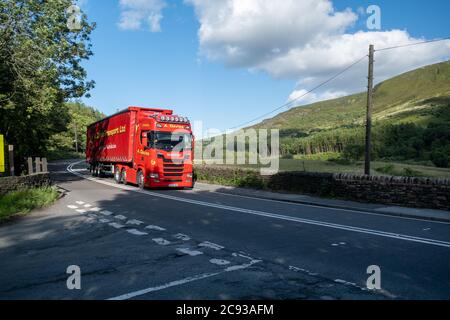 A Davies Haulage Scania truck pulling a curtainsider trailer driving along the A628 Woodhead Pass in Yorkshire on a sunny Summer afternoon Stock Photo