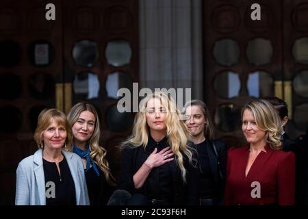 Actress Amber Heard, alongside her sister Whitney Henriquez (second right) and lawyer Jen Robinson (right), as she gives a statement outside the High Court in London on the final day of hearings in Johnny Depp's libel case against the publishers of The Sun and its executive editor, Dan Wootton. After almost three weeks, the biggest English libel trial of the 21st century is drawing to a close, as Mr Depp's lawyers are making closing submissions to Mr Justice Nicol. Stock Photo