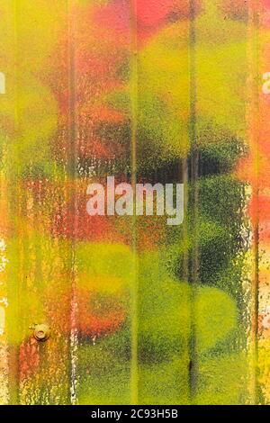 Metal siding painted in different colors of yellow, orange and green. Stock Photo