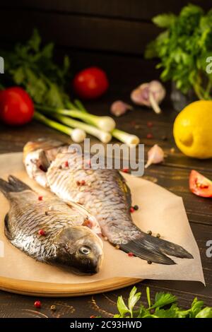 Fresh carassius on the board, river fish crucian carp with spices ready for frying or roasting in the oven Stock Photo