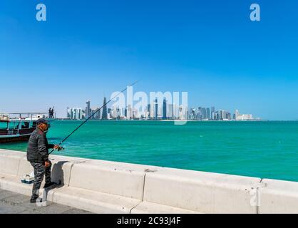 Local man fishing in front of the skyline of the West Bay Central Business District, The Corniche, Doha, Qatar, Middle East Stock Photo