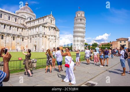 Pisa, Italy - August 14, 2019: Group of tourists posing doing funny portraits in front of the Leaning Tower of Pisa, region of Tuscany, Italy