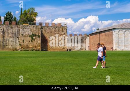 Pisa, Italy - August 14, 2019: Tourists walking on the background of the Le mura di Pisa. These were the walls of the city of Pisa, now they surround Stock Photo