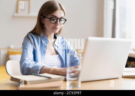 Working at home allow me for flexible working. Pleasant happy young woman freelancer working on computer at home. Stock Photo