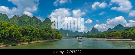 Yangshuo, China - August 2019 : Panoramic view of the sightseeing boat carrying tourists sailing among stunning karst mountain scenery on the magnific Stock Photo